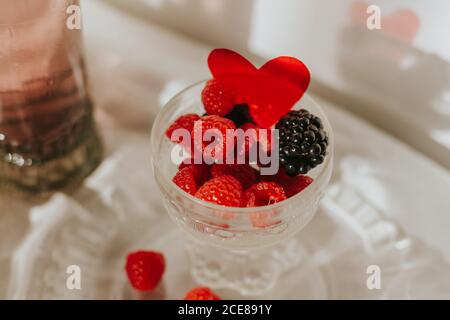 Superbe composition avec bouteille et verres de style vintage sur une table blanche disposée avec une assiette et un gobelet avec des baies Banque D'Images