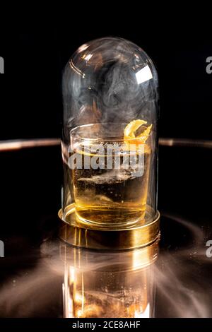 Verre d'alcool placé sous le dôme avec de la fumée table réfléchissante dans la barre Banque D'Images