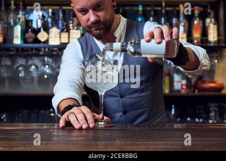 Un jeune barman professionnel tient une bouteille tout en préparant un cocktail la barre Banque D'Images