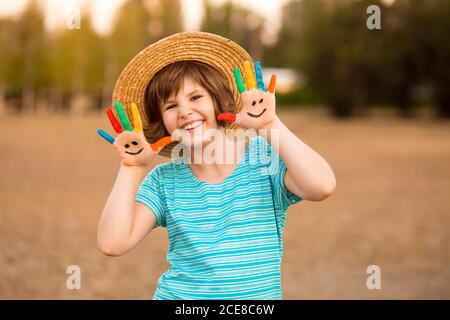 Bonne petite fille souriante avec les mains dans la peinture jouer à l'extérieur dans le parc d'été Banque D'Images