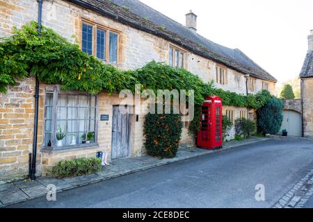 Un cottage de chaume construit à partir de la pierre de jambon locale et une boîte téléphonique rouge historique dans le centre du village de Montacute, Somerset, Angleterre, Royaume-Uni Banque D'Images
