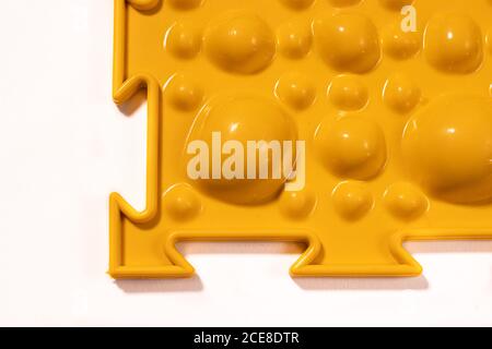 Tapis orthopédique jaune sous forme de petites pierres sur fond blanc pour le massage des pieds. Prévention des pieds plats des enfants Banque D'Images