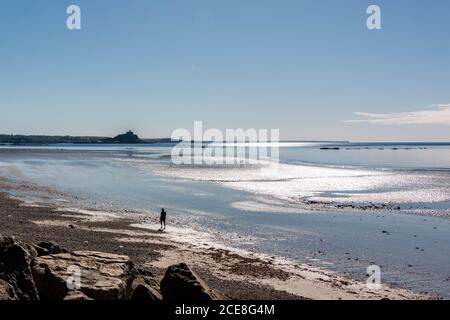 Personne marchant le long de la plage à Penzance en direction de St Michael's Mount à marée basse Banque D'Images