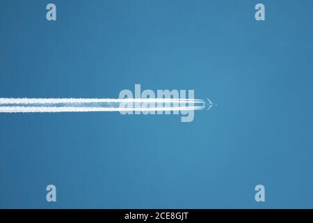 Gros plan sur l'avion contrail contre le ciel bleu clair Banque D'Images