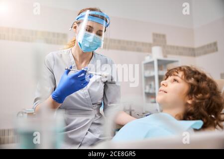 Un dentiste qualifié donne un coup d'anesthésique à l'enfant Banque D'Images