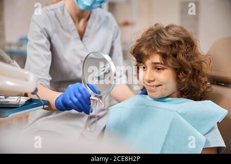 Enfant dans la clinique dentaire souriant à sa réflexion Banque D'Images