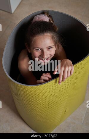 De dessus de rire adolescente assis sur le sol enveloppé dans un tapis de yoga vert souriant à l'appareil photo Banque D'Images