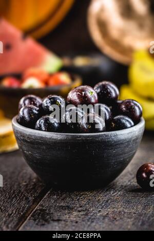 Jaboticaba ou jabuticaba, fruit brésilien et sud-américain, dans un pot d'argile. Avec des fruits tropicaux en arrière-plan. Banque D'Images