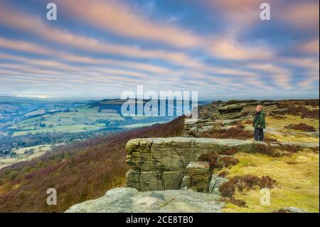 Un homme admire la vue depuis Curbar Edge. Banque D'Images