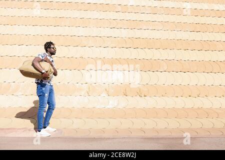 jeune homme noir élégant avec lunettes de soleil et un grand sac de voyage, concept de liberté et de mode de vie de voyageur, espace de copie pour le texte Banque D'Images