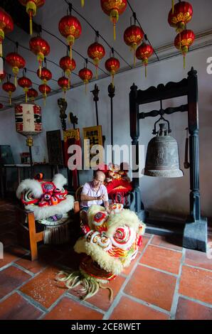 Georgetown, Penang/Malaysia - Jul 08 2016: Un vieil homme nettoie la tête de danse traditionnelle chinoise du lion dans le temple. Banque D'Images