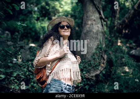 Vue latérale de la femme dans des vêtements chauds avec sac à dos marchant dans la forêt de conifères. Banque D'Images