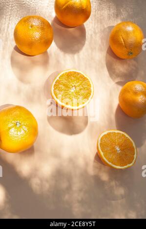 Du dessus des moitiés d'oranges mûres disposées sur l'orange arrière-plan avec ombres Banque D'Images