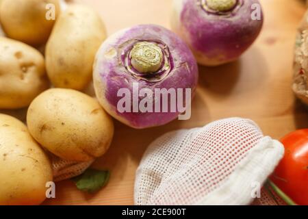 Assortiment de légumes et de fruits en papier et coton en maille emballages réutilisables placés sur une table en bois dans la cuisine Banque D'Images