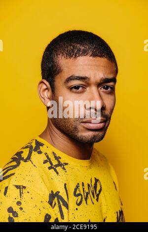 Race mixte jeune homme regardant la caméra avec une expression sérieuse sur fond jaune Banque D'Images