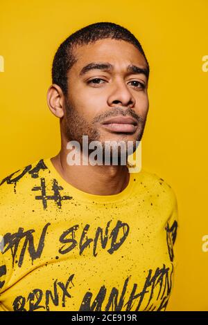 Race mixte jeune homme regardant la caméra avec une expression sérieuse sur fond jaune Banque D'Images