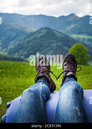 Fille en bottes de randonnée et jeans bleu prenant un repos et appréciant la vue magnifique sur la montagne. Banque D'Images