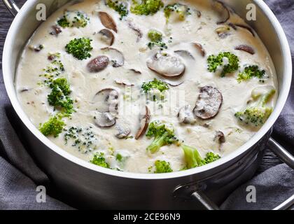 Soupe de brocoli aux champignons dans une casserole avec des ingrédients à l'arrière-plan, vue d'en haut, gros plan Banque D'Images