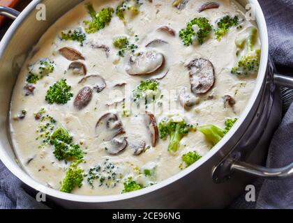 Soupe de brocoli aux champignons dans une casserole avec des ingrédients à l'arrière-plan, vue d'en haut, gros plan Banque D'Images