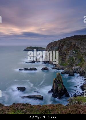 Vue sur le coucher du soleil vers le phare de South Stack sur Anglesey. Banque D'Images