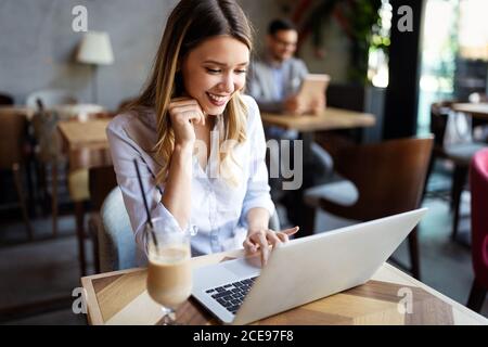 Portrait d'une jeune belle businesswomen bénéficiant du café pendant le travail sur ordinateur portable, Banque D'Images