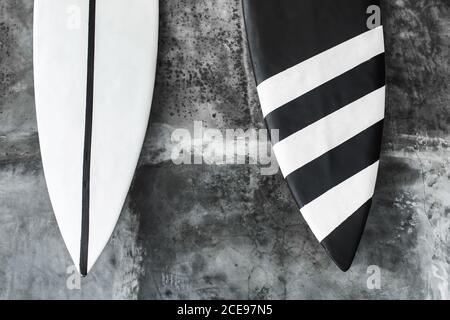 Planche de surf noire et blanche sur fond de mur en béton gris. Décoration intérieure contemporaine de café dans un style minimaliste. Texture sombre. Banque D'Images