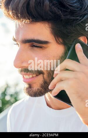 portrait d'un beau jeune homme souriant et parlant sur son téléphone au coucher du soleil, concept de technologie et de style de vie urbain, espace de copie pour le texte Banque D'Images