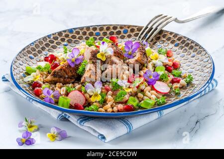 Salade de canard croustillante, d'épeautre et de grenade garnie de fleurs de alto Banque D'Images