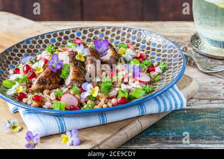 Salade de canard croustillante, d'épeautre et de grenade garnie de fleurs de alto Banque D'Images