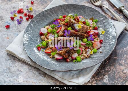 Salade de canard croustillante, d'épeautre et de grenade garnie de fleurs de alto Banque D'Images