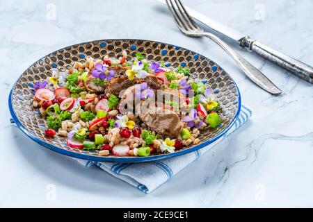 Salade de canard croustillante, d'épeautre et de grenade garnie de fleurs de alto Banque D'Images