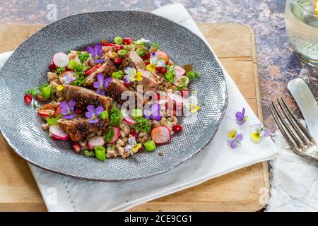 Salade de canard croustillante, d'épeautre et de grenade garnie de fleurs de alto Banque D'Images