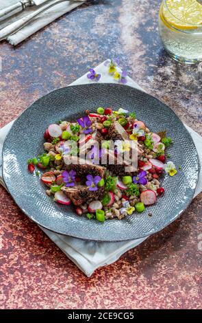 Salade de canard croustillante, d'épeautre et de grenade garnie de fleurs de alto Banque D'Images