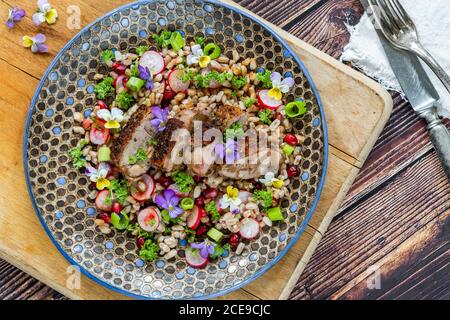 Salade de canard croustillante, d'épeautre et de grenade garnie de fleurs de alto - vue sur le dessus Banque D'Images