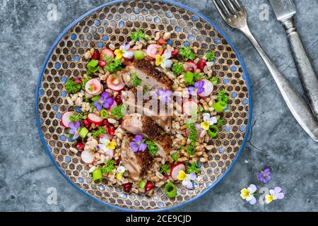 Salade de canard croustillante, d'épeautre et de grenade garnie de fleurs de alto - vue sur le dessus Banque D'Images