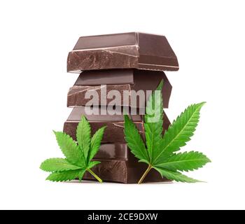 Gros plan de la pile de morceaux de chocolat noir avec Deux feuilles de marijuana ou de chanvre isolées sur fond blanc Banque D'Images