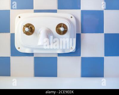 Ancien robinet d'eau intérieur dans la salle de bains sur le bleu et mur de carreaux blancs Banque D'Images