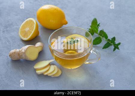 Thé au gingembre dans une tasse de verre avec citron et menthe table en pierre Banque D'Images