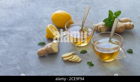 Deux tasses en verre de thé au gingembre avec des citrons et des feuilles de menthe. Espace pour le texte Banque D'Images