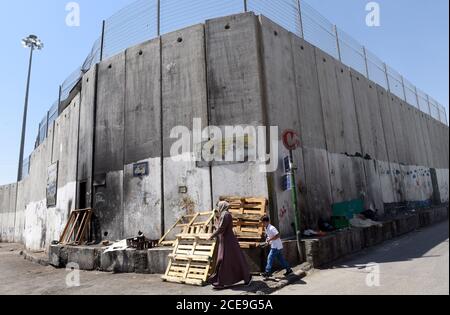 Camp de réfugiés de Shurafat, Israël. 31 août 2020. Les Palestiniens marchent à côté du mur de séparation israélien autour du camp de réfugiés de Shurafat, près de Jérusalem, le lundi 31 août 2020. Le conseiller présidentiel américain Jared Kushner a appelé les Palestiniens à reprendre les négociations avec Israël et à ne pas être « dans le passé » à leur arrivée à l'AUE lors du premier vol direct entre Israël et Abu Dhabi. Photo par Debbie Hill/UPI crédit: UPI/Alay Live News Banque D'Images