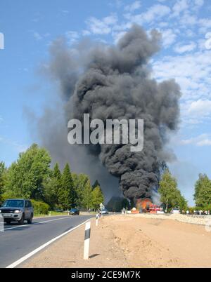 Chariot en feu avec fumée noire sur la route Banque D'Images