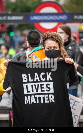Une femme portant un masque facial tient un T-shirt noir Lives Matter pendant la marche de millions de personnes de Notting Hill à Hyde Park. Banque D'Images