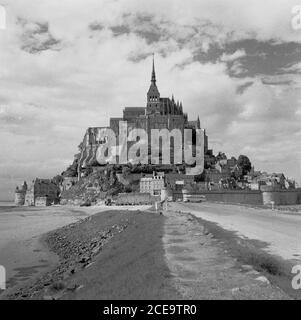 France, années 1950, vue historique du Mont-Saint-Michel, Normandie, une île marémotrice et commune avec une ancienne abbaye bénédictine médiévale. L'île se trouve au large de la côte nord-ouest de la France, à l'embouchure du fleuve Couesnon. Le mont St Michael's à Cornwall, au Royaume-Uni, bien que plus petit, est semblable au Mont-Michel. Banque D'Images