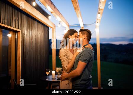 Jeune couple dansant dehors au crépuscule, week-end loin dans la maison de conteneurs dans la campagne. Banque D'Images