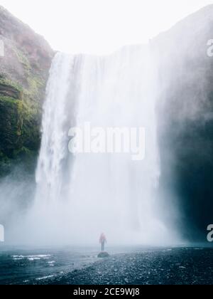Personne méconnaissable se tenant sous la montagne de la cascade. Prise de vue verticale en extérieur. Banque D'Images