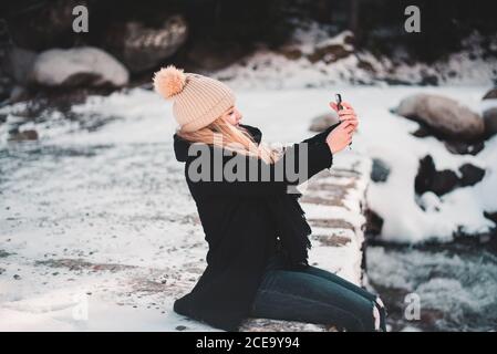 Femme prenant le selfie à la rivière en hiver Banque D'Images