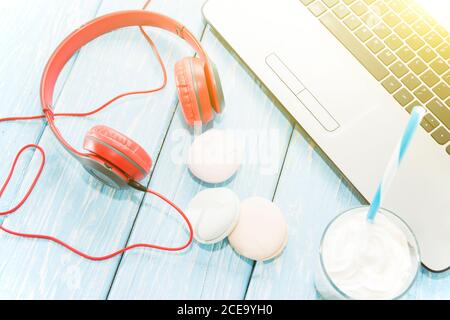Ordinateur portable ouvert avec tasse de café blanc, guimauves et écouteurs rouges. Banque D'Images