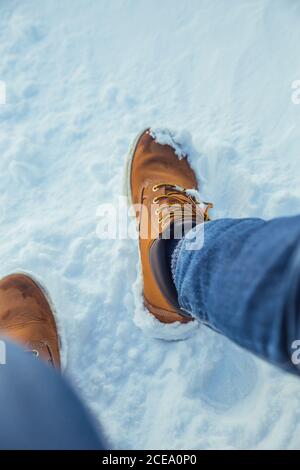 Rognez les jambes des hommes en jeans et en bottes d'hiver, assis sur la neige par temps ensoleillé, près des collines de Cerdanya, en France Banque D'Images