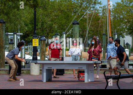 Annapolis, MD 08/21/2020: Deux hommes jouent au ping-pong (tennis de table) dans le parc près de la marina d'Annapolis. Ils ont des spectateurs qui regardent le jeu. Banque D'Images