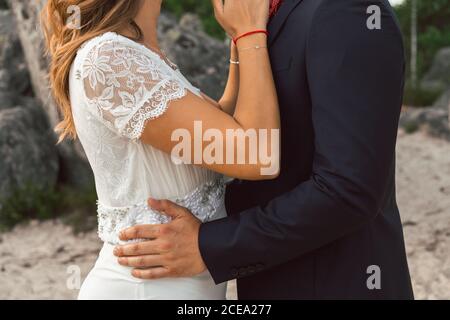 Vue de côté rognée de gaie homme tendre et femme touchant avec le nez et regardant l'un l'autre avec amour le jour du mariage Banque D'Images